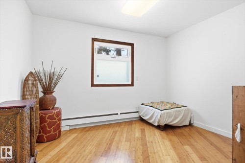 This room features light hardwood flooring and a window with a dark wood trim - 11026 110 Avenue, Edmonton, AB - Indoor