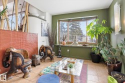 This inviting sunroom features a bay window, tile flooring, and walls with a warm green hue - 