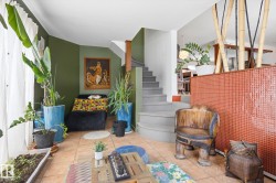 This living area features tile flooring, a staircase with gray treads, and a partial wall with a textured orange surface - 