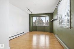 Living space featuring hardwood flooring, a bay window with blinds, and track lighting - 