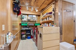 Laundry area with wood paneling on the walls and ceiling, featuring a red washing machine and dryer, and built-in shelving for storage - 