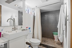 The bathroom features a modern rectangular vessel sink with a contemporary faucet, a toilet, and a tiled shower area with a shower curtain - 