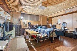 Living area featuring wood paneling on the walls, a slatted wood ceiling, and wood-look flooring - 