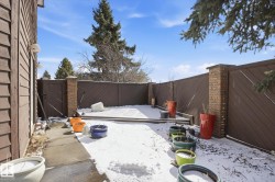 The property features a private outdoor area with a brown slatted fence, brick pillars, and a paved walkway - 