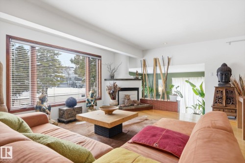 The living area features a large window with horizontal blinds, hardwood flooring, and a fireplace with a mantel - 11026 110 Avenue, Edmonton, AB - Indoor Photo Showing Living Room With Fireplace