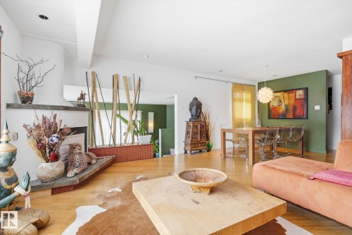 This spacious living area features hardwood floors and a fireplace with a stone mantel - 11026 110 Avenue, Edmonton, AB - Indoor Photo Showing Living Room