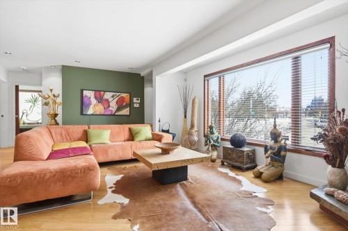 This living area features light hardwood flooring and a large window with horizontal blinds - 11026 110 Avenue, Edmonton, AB - Indoor Photo Showing Living Room