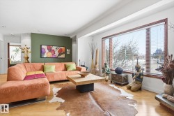 This living area features light hardwood flooring and a large window with horizontal blinds - 
