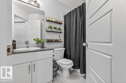 Bathroom featuring a vanity with an oval sink, a toilet, and a shower area with a dark shower curtain - 3708 42 Avenue, Beaumont, AB - Indoor Photo Showing Bathroom