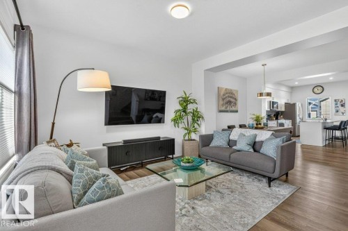 The living area features hardwood floors and recessed lighting, with a view towards the kitchen which includes an island with seating - 3708 42 Avenue, Beaumont, AB - Indoor Photo Showing Living Room