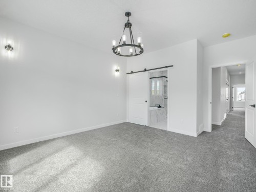 This room features grey carpet, white walls, and a black chandelier - 239 Kinglet Boulevard Nw, Edmonton, AB - Indoor Photo Showing Other Room