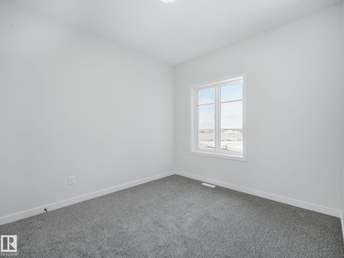 The property features light gray carpeting, white walls, and a large window providing natural light - 239 Kinglet Boulevard Nw, Edmonton, AB - Indoor Photo Showing Other Room