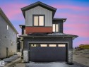 The property features a modern exterior with horizontal siding in varying shades, a prominent garage door with rectangular windows, and stone accents on the garage pillars - 239 Kinglet Boulevard Nw, Edmonton, AB  - Outdoor 