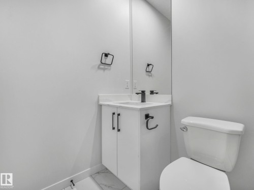 This bathroom features a contemporary white vanity with a countertop, a toilet, and a mirror - 239 Kinglet Boulevard Nw, Edmonton, AB - Indoor Photo Showing Bathroom