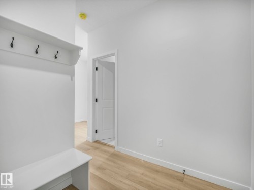 The entrance features a built-in bench and coat rack with black hooks, light wood-style flooring, and white walls - 239 Kinglet Boulevard Nw, Edmonton, AB - Indoor Photo Showing Other Room