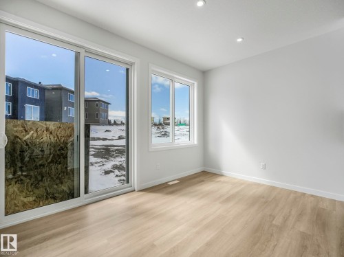 This bright room features light-colored flooring, recessed lighting, and large sliding glass doors providing ample natural light - 239 Kinglet Boulevard Nw, Edmonton, AB - Indoor Photo Showing Other Room