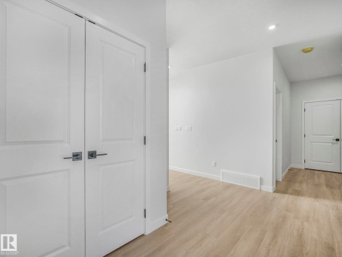Foyer featuring light-toned flooring, white walls, and white panel doors with contemporary hardware - 239 Kinglet Boulevard Nw, Edmonton, AB - Indoor Photo Showing Other Room