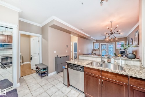 The kitchen features a double basin sink, stainless steel dishwasher, and granite countertops - 307 10121 80 Avenue, Edmonton, AB - Indoor Photo Showing Kitchen With Double Sink