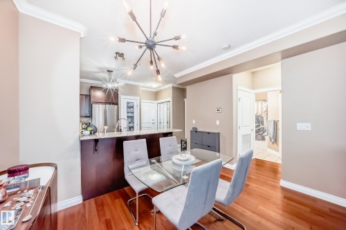 Dining area featuring hardwood floors and a contemporary chandelier - 307 10121 80 Avenue, Edmonton, AB - Indoor Photo Showing Dining Room