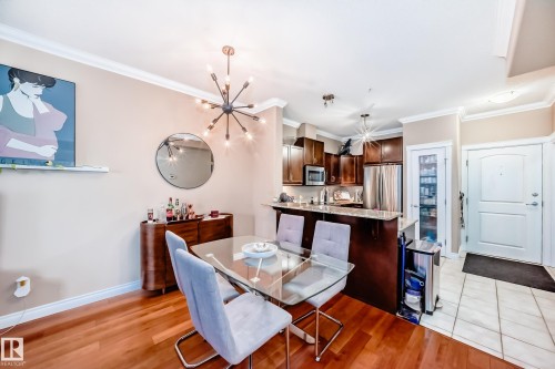 The property features hardwood flooring in the main living space and a kitchen with stainless steel appliances, granite countertops, and dark wood cabinetry - 307 10121 80 Avenue, Edmonton, AB - Indoor