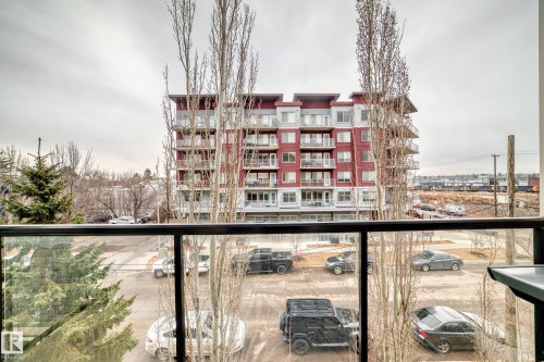The property features a balcony with a glass railing, providing views of the surrounding urban landscape and other residential buildings - 307 10121 80 Avenue, Edmonton, AB - Outdoor With Balcony