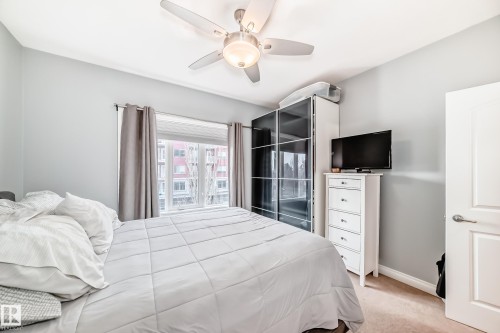 This bedroom features neutral-toned walls, a window with blinds and drapes, and a ceiling fan with integrated lighting - 307 10121 80 Avenue, Edmonton, AB - Indoor Photo Showing Bedroom