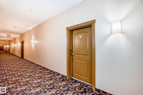 The property features a private entry door with a peephole, set within a well-lit hallway - 307 10121 80 Avenue, Edmonton, AB - Indoor