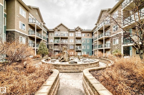 This property features multi-story buildings with balconies, stone accents, and a central courtyard - 307 10121 80 Avenue, Edmonton, AB - Outdoor With Balcony With Facade