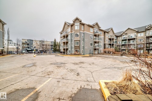 The property is part of a multi-story building featuring balconies and a mix of siding and stone exterior finishes - 307 10121 80 Avenue, Edmonton, AB - Outdoor With Balcony