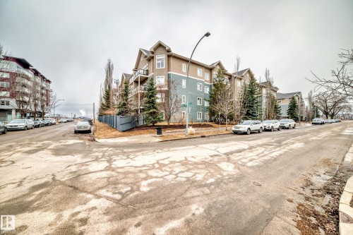 This property features a multi-story building with a light brown and teal facade, balconies, and dormer windows - 307 10121 80 Avenue, Edmonton, AB - Outdoor