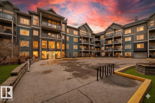 The property features a multi-story building with balconies, large windows, and a combination of stone and siding exterior finishes - 307 10121 80 Avenue, Edmonton, AB - Outdoor With Balcony