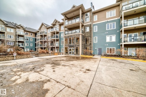 The property features a stone and siding exterior with balconies and a prominent central entrance - 307 10121 80 Avenue, Edmonton, AB - Outdoor With Balcony With Facade