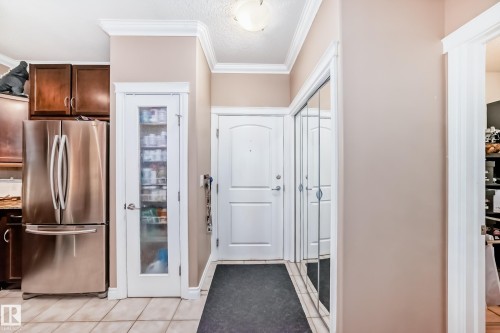 Entryway with a white door, mirrored closet doors, and crown molding - 307 10121 80 Avenue, Edmonton, AB - Indoor Photo Showing Other Room