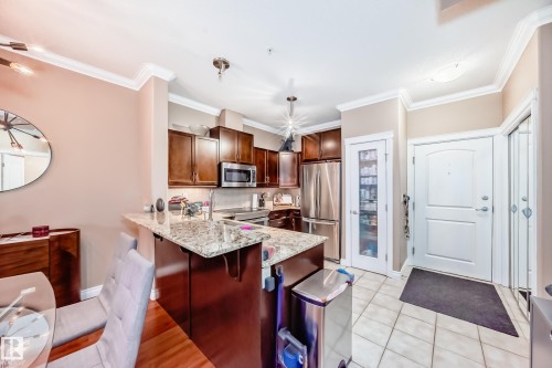 Kitchen featuring wood cabinetry, stainless steel appliances, and granite countertops - 307 10121 80 Avenue, Edmonton, AB - Indoor Photo Showing Kitchen