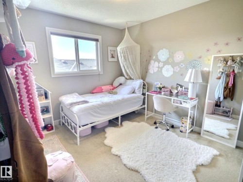 This room features a window providing natural light, carpeted flooring, and a decorative wall treatment - 5718 Rue Eaglemont, Beaumont, AB - Indoor Photo Showing Bedroom