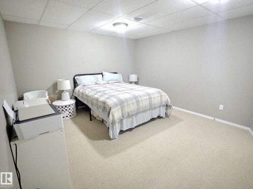Bedroom with neutral-toned walls, light-colored carpeting, and a drop ceiling - 5718 Rue Eaglemont, Beaumont, AB - Indoor Photo Showing Bedroom