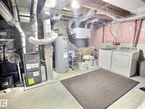 The property features a utility area with a furnace, water heater, and laundry appliances - 5718 Rue Eaglemont, Beaumont, AB - Indoor Photo Showing Laundry Room
