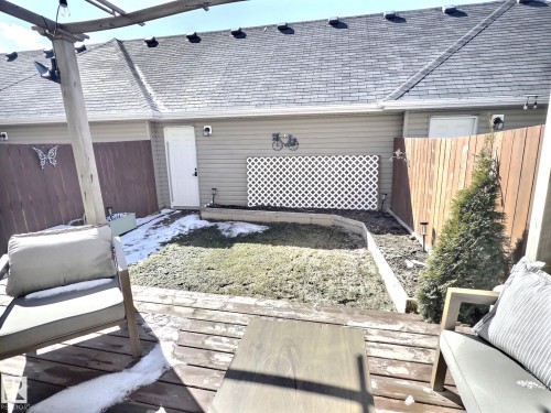 The property features a private backyard with a wooden fence and a trellis accent - 5718 Rue Eaglemont, Beaumont, AB - Outdoor With Deck Patio Veranda With Exterior