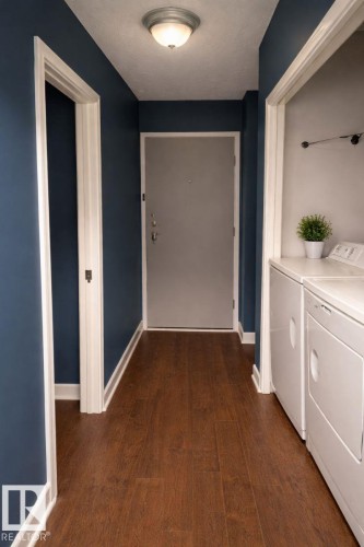 Entryway featuring wood flooring, a ceiling-mounted light fixture, and a laundry area with appliances - 4 3819 76 Street, Edmonton, AB - Indoor
