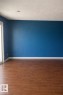 This room features hardwood flooring, a bright blue accent wall, and a recessed ceiling light - 4 3819 76 Street, Edmonton, AB  - Indoor Photo Showing Other Room 