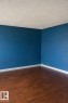 The room features rich brown flooring, blue walls, and white baseboards - 4 3819 76 Street, Edmonton, AB  - Indoor Photo Showing Other Room 