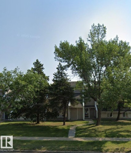 The property features a multi-story building with a light-colored facade, dark roof, and prominent entryway - 4 3819 76 Street, Edmonton, AB - Outdoor