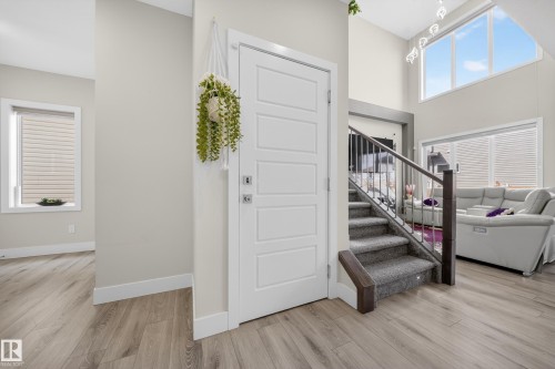 Entryway featuring light-toned flooring, a white paneled door, and a staircase with carpeted steps and a metal railing - 449 Roberts Crescent, Leduc, AB - Indoor Photo Showing Other Room