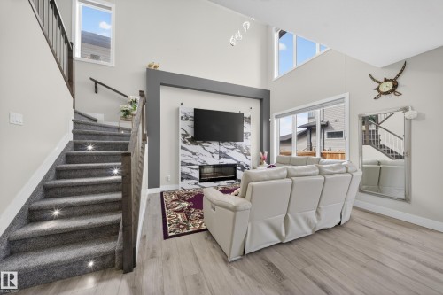 The inviting living area features high ceilings, large windows providing natural light, and light-colored flooring - 449 Roberts Crescent, Leduc, AB - Indoor