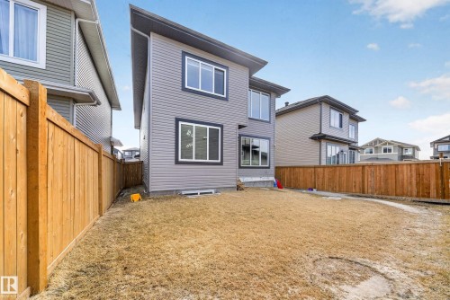 The property features a two-story exterior with light gray siding and white-framed windows, set against a blue sky with scattered clouds - 449 Roberts Crescent, Leduc, AB - Outdoor With Exterior