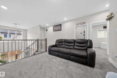 Upper level landing with grey carpet flooring, a contemporary chandelier, and an open railing overlooking the lower level - 449 Roberts Crescent, Leduc, AB - Indoor