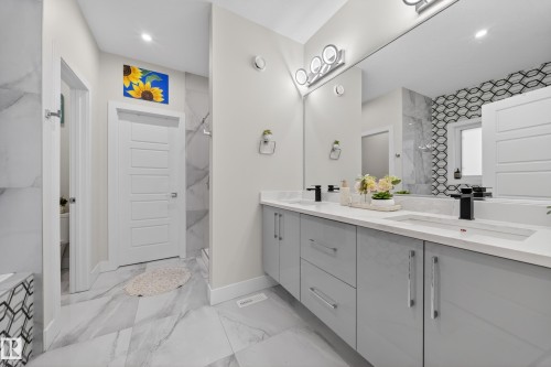 The bathroom features a double vanity with light gray cabinetry, white countertops, and black faucets - 449 Roberts Crescent, Leduc, AB - Indoor Photo Showing Bathroom