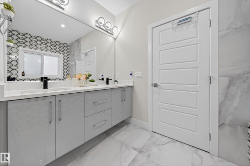 This bathroom features a double vanity with light gray cabinetry, white countertops, and black faucets - 449 Roberts Crescent, Leduc, AB - Indoor Photo Showing Bathroom