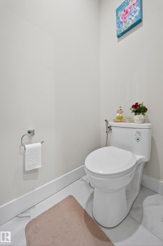 The property features a well-maintained toilet with a bidet sprayer, set against light-colored walls and white baseboards - 449 Roberts Crescent, Leduc, AB - Indoor Photo Showing Bathroom