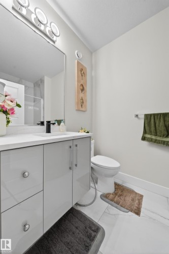 The bathroom features a modern vanity with a white countertop and a rectangular sink, complemented by a large wall-mounted mirror - 449 Roberts Crescent, Leduc, AB - Indoor Photo Showing Bathroom